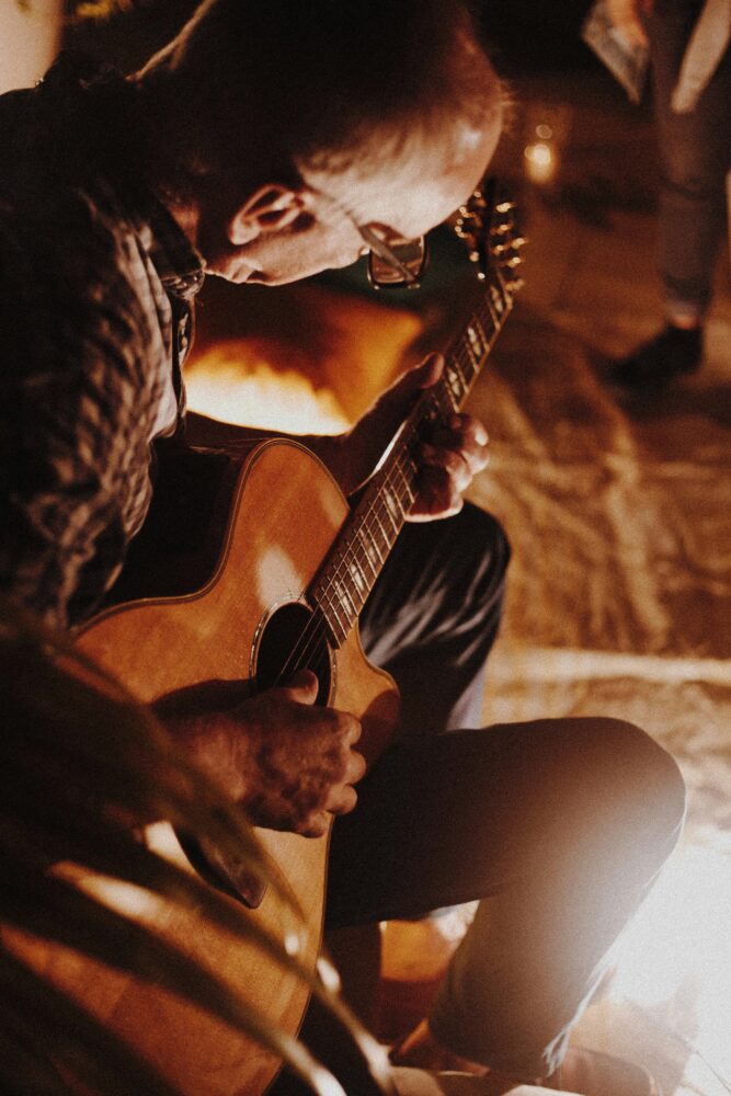 pexels photo 1587284 1587284 Man playing acoustic guitar by firelight creating a cozy atmosphere.